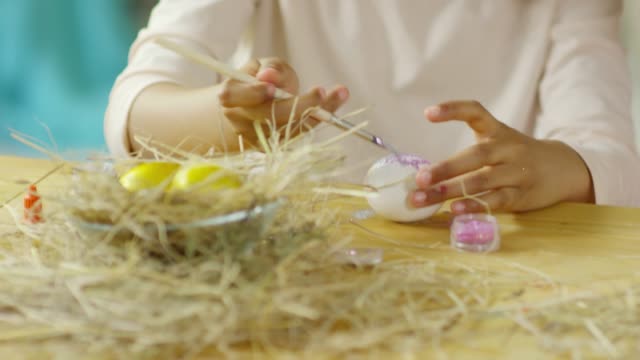 Pequeña-chica-africana-decorando-huevo-de-Pascua-con-Glitter