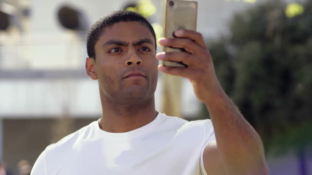 Fokussierte-afroamerikanische-junge-Mann-hält-Smartphone.
