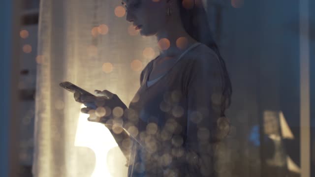 Mujer-conectando-con-su-teléfono-al-lado-de-una-ventana