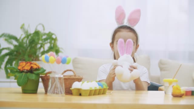 Little-cute-and-adorable-girl-is-smiling-and-playing-with-bunny's-ears.-Concept-Easter-holiday.