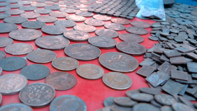 Vintage-Indian-coins-in-large-piles-lie-on-a-red-counter-in-Rishikesh,-India