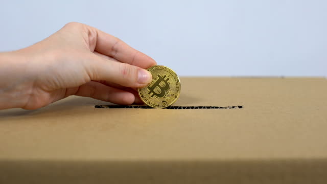 Hand-putting-bitcoin-in-carton-box,-online-donation-service,-internet-payment