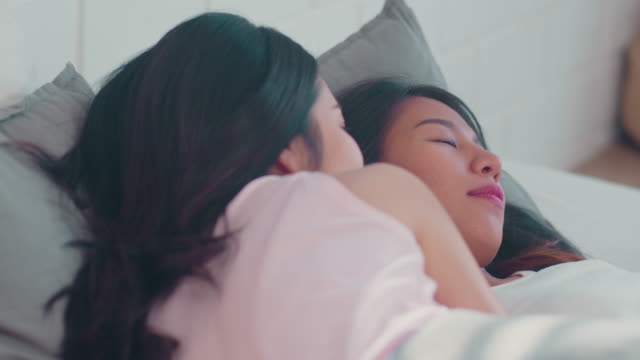 Asiatische-Lesbische-Paar-entspannen-sich-zusammen-nach-dem-Aufwachen-liegend-auf-dem-Bett-im-Schlafzimmer.