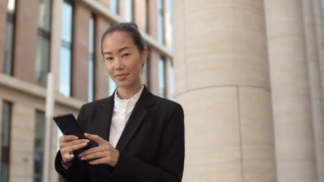 Asiatische-Geschäftsfrau-mit-Telefon-draußen