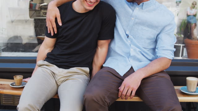 Close-Up-Of-Loving-Male-Gay-Couple-Hugging-Outside-Coffee-Shop