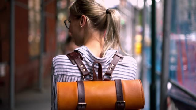 Back-view-of-female-traveller-with-stylish-touristic-backpack-calling-to-friend-for-talking