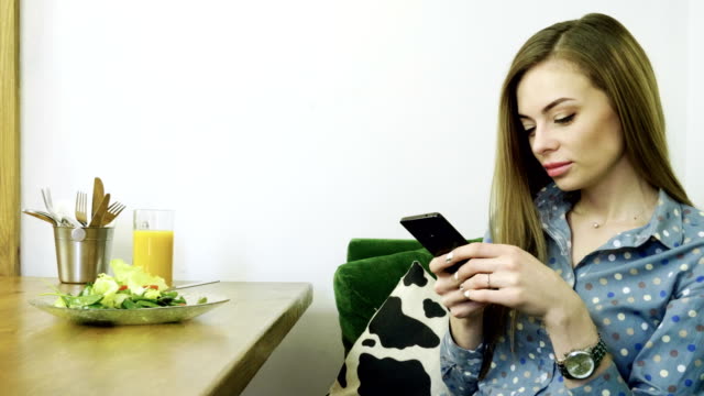 Attractive-young-happy-woman-using-mobile-phone-during-resting-in-a-cafe.-4K