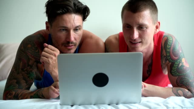 Schwules-Paar-im-Bett-mit-Laptop-Computer.-Konzentrieren-Sie-sich-auf-das-Display.