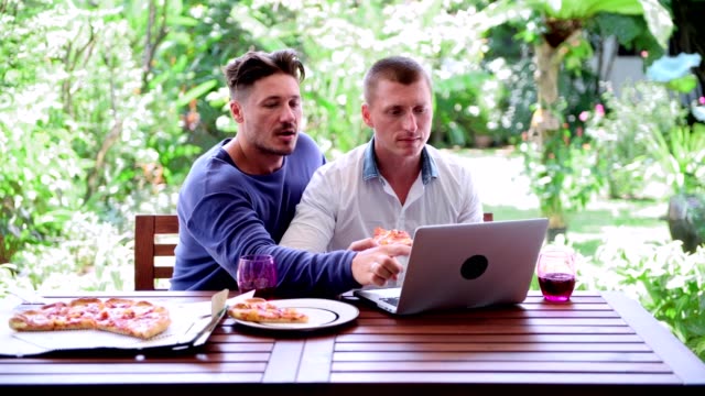 Gay-couple-having-pizza-for-lunch.-Pointing-at-screen.
