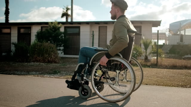 Junger-Mann-mit-gelähmten-Beinen-im-Rollstuhl-läuft-allein-in-den-Straßen-der-Stadt