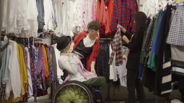 Mujer-en-silla-de-ruedas-comprando-ropa-con-amigas-femeninas