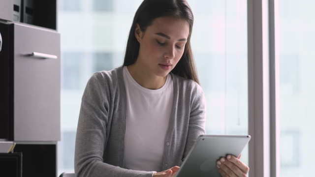 Fokussierte-junge-Geschäftsfrau,-die-mit-digitalem-Tablet-im-Büro-hält
