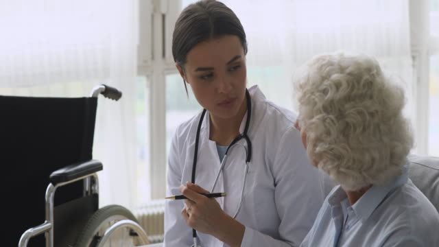 Young-woman-doctor-consult-disabled-handicapped-old-grandma-patient