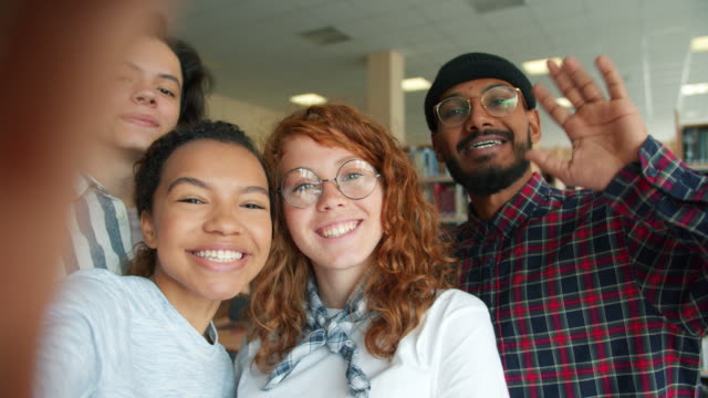 Multi-rassische-Gruppe-von-jungen-Menschen,-die-Selfie-in-College-Bibliothek-lächelnd