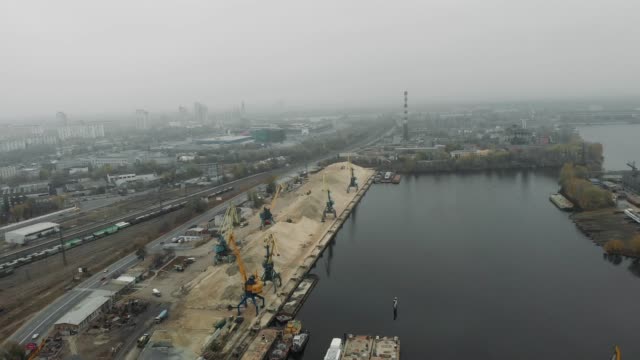 Hafenkrane-entladen-Flusssand-von-Binnenschiffs-in-Docks-mit-Baggern-und-Lastwagen,-die-sich-bewegen.-Konzept-der-Industriedocks
