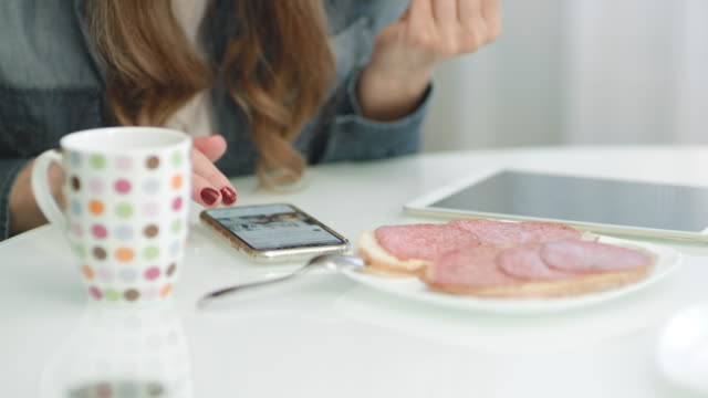 Closeup-Frau-Hände-mit-Smartphone-während-des-Frühstücks-in-der-Küche.