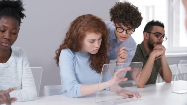 Lehrer-hilft-Schülern-bei-der-Ausführung-von-Aufgaben-auf-interaktivem-AR-Tablet-Computer