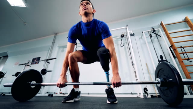 Ein-Mann-mit-einem-bionischen-Bein-beginnt,-schwere-Gewichte-in-einem-Fitnessstudio-zu-heben