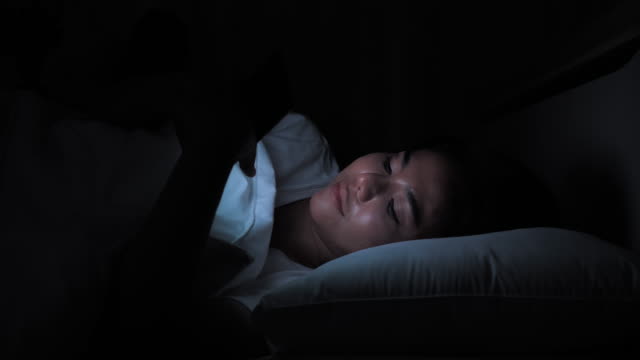 Nahaufnahme-asiatische-Frau-mit-Smartphone-auf-dem-Bett-in-zu-Hause-in-der-Nacht