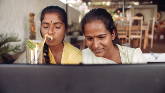 Dos-mujeres-que-beben-bebidas-usando-tecnología-en-café