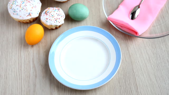 Hands-put-on-the-table-a-plate-with-a-Easter-cake-with-white-icing.