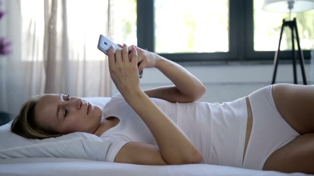 Frau-im-Bett-überprüfen-soziale-apps-mit-smartphone