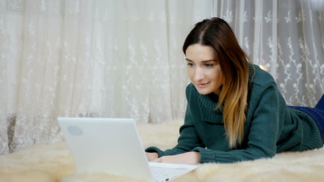 Pretty-girl-lays-on-the-carpet-on-floor-and-uses-laptop