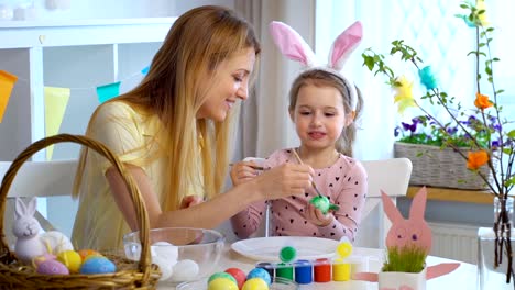 Happy-Easter!-Mother-and-her-little-daughter-wearing-funny-rabbit-ears-coloring-easter-eggs