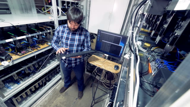 Mining-rig-with-a-male-specialist-in-it-controlling-bitcoin-mining-process