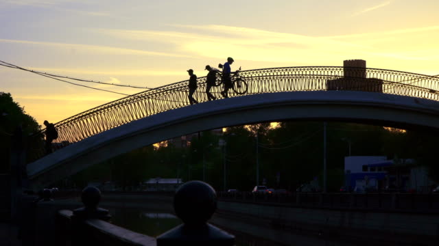 siluetas-de-personas-que-cruzan-el-canal-en-un-puente-jorobado
