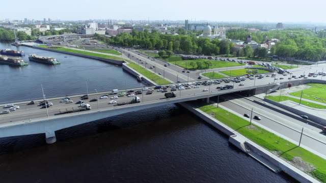 Multi-level-road-junction-on-near-blue-river-with-bridge-and-barges