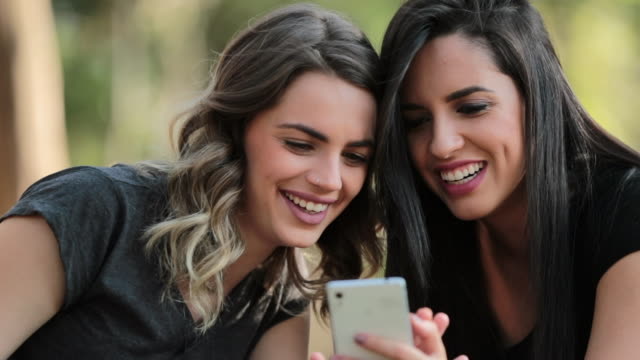 Ehrliche-Freundinnen-Blick-auf-ihr-Handy-im-Freien-auf-social-media