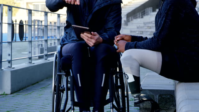 Dos-discapacitados-atletismo-discutiendo-sobre-tableta-digital-4k