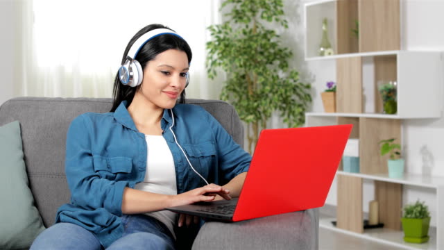 Glückliche-Frau-mit-Kopfhörer-Laptop-Inhalte-durchsuchen