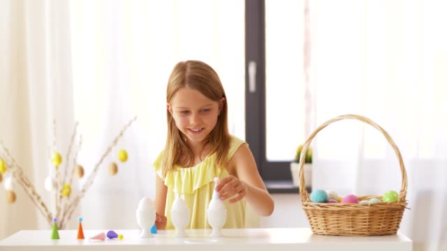 Chica-feliz-decorando-huevos-de-Pascua-en-casa