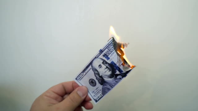 Hand-hält-brennende-hundert-Dollar-Banknote
