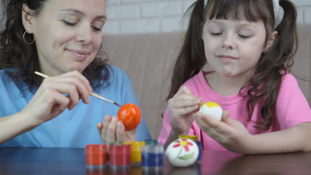 A-woman-with-a-child-paint-eggs-for-Easter.