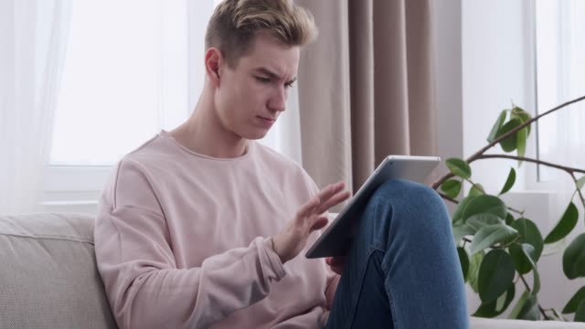 Hombre-usando-la-tableta-digital-en-el-sofá-en-casa