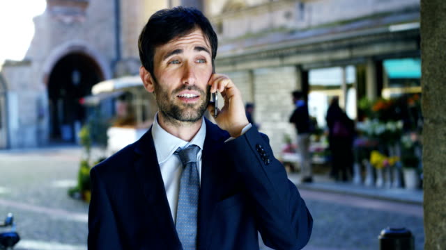 A-businessman-answering-the-phone,-send-messages-and-smiles-for-the-beautiful-job-news-and-in-the-background-you-see-a-people.