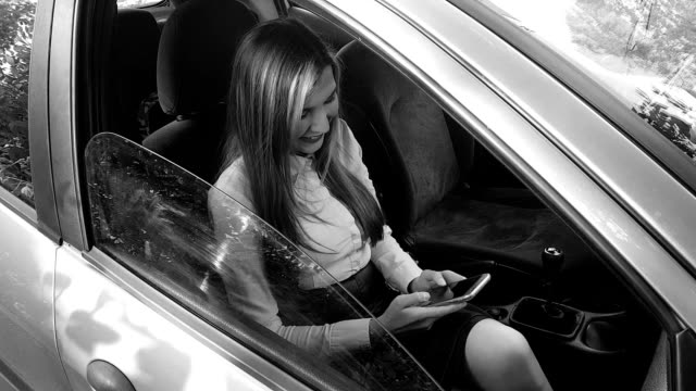 Schönes-Mädchen-mit-ihrem-Handy-im-Auto
