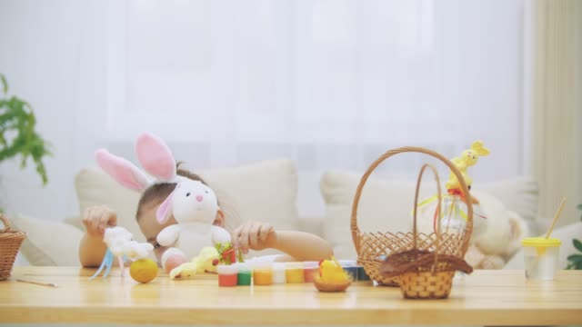 Little-cute-and-adorable-girl-is-smiling-and-playing-with-colorful-chicken's-eggs-and-bunnies.-Concept-Easter-holiday.
