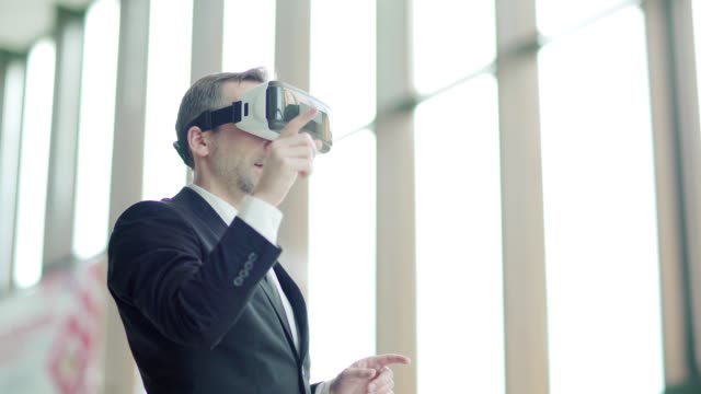 Medium-shot-of-middle-aged-businessman-in-formal-suit-wearing-virtual-reality-glasses-and-swiping-visualized-data