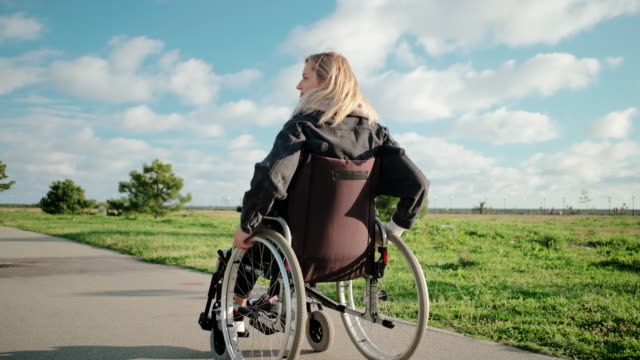 Mujer-adulta-discapacitada-está-conduciendo-su-silla-de-ruedas-en-el-área-del-parque-en-un-día-soleado
