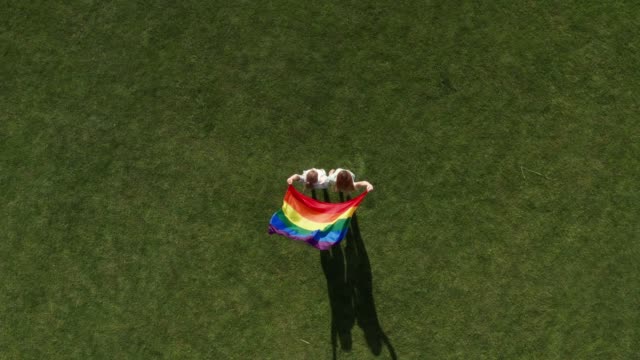 Drone-shot-of-gay-couple-with-fluttering-lgbt-flag