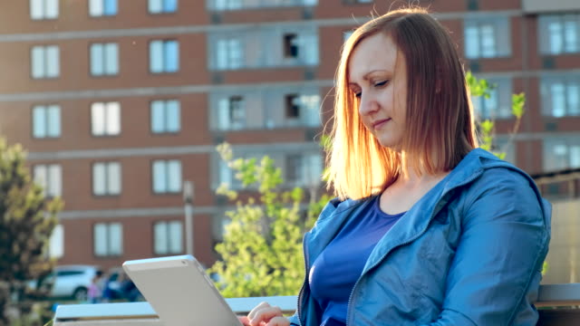 Frau-mit-Tablet-Computer-sitzt-auf-Bank-in-der-Stadt