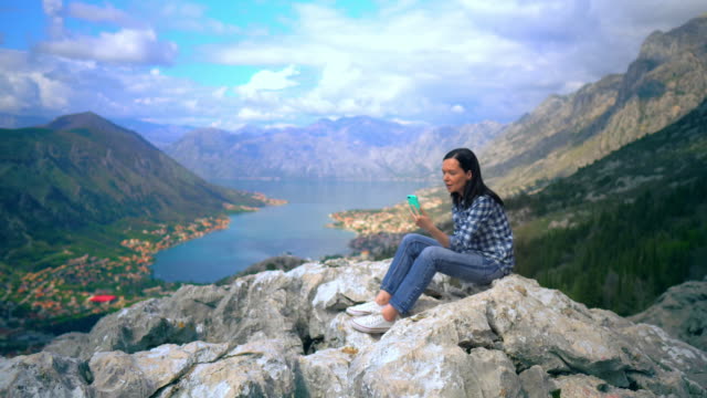 Young-Woman-Looking-into-smartphone-on-mountain-peak