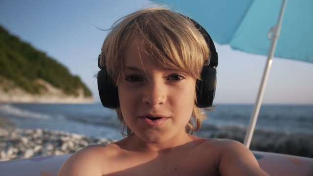 Lindo-niño-usando-teléfono-inteligente-en-la-playa