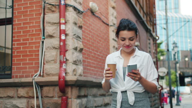 Portrait-of-attractive-girl-holding-smartphone-and-take-out-coffee-walking