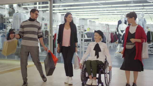 Glückliche-Frau-im-Rollstuhl-und-ihre-Freunde-Einkaufen-in-Mall