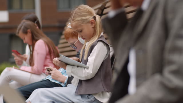 Blonde-Schulmädchen-mit-Tablet-im-Freien